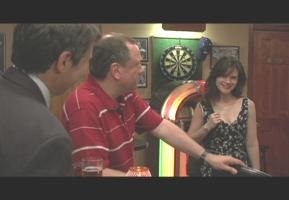 A man and woman playing darts in front of two other men.